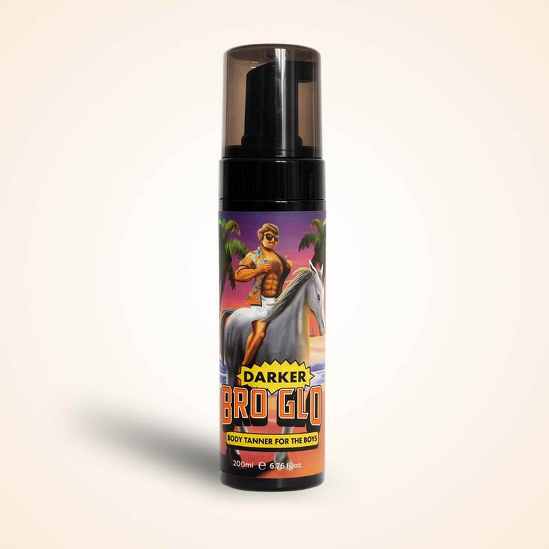 A dark self-tanning foam bottle with a black pump top and colorful tropical illustration on the label.