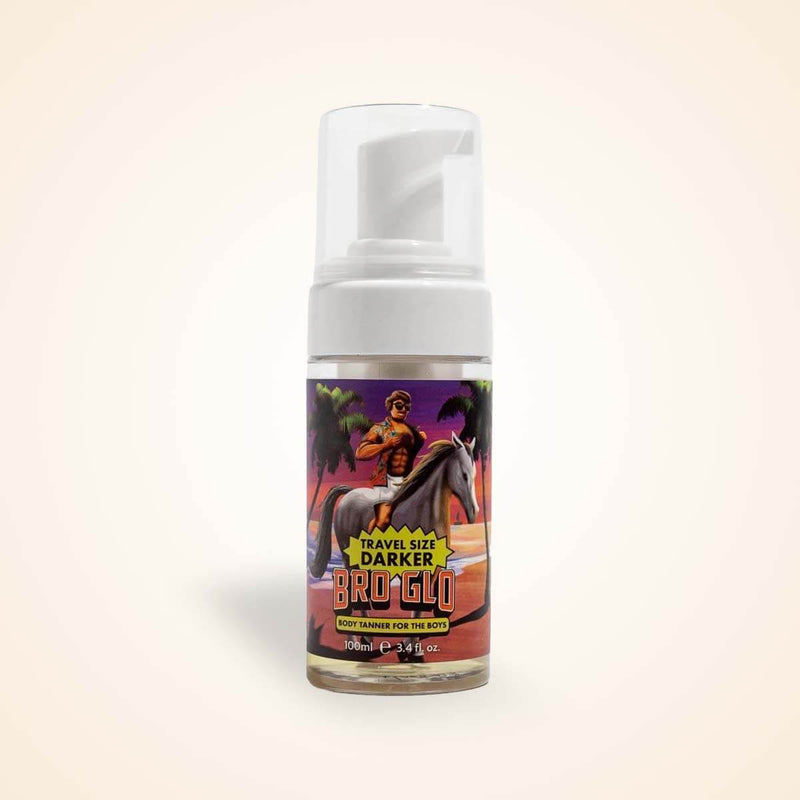 White pump bottle containing bronze liquid tanner with colorful tropical artwork label on beige background.