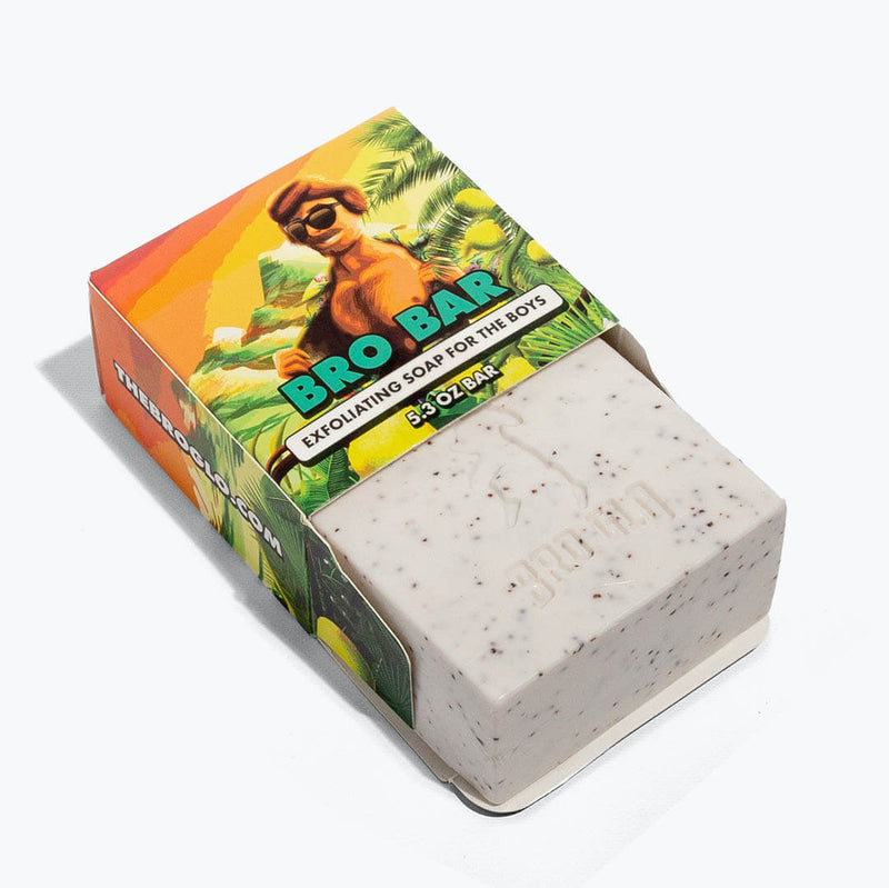 White exfoliating soap bar with speckled texture displayed next to colorful tropical-themed packaging.