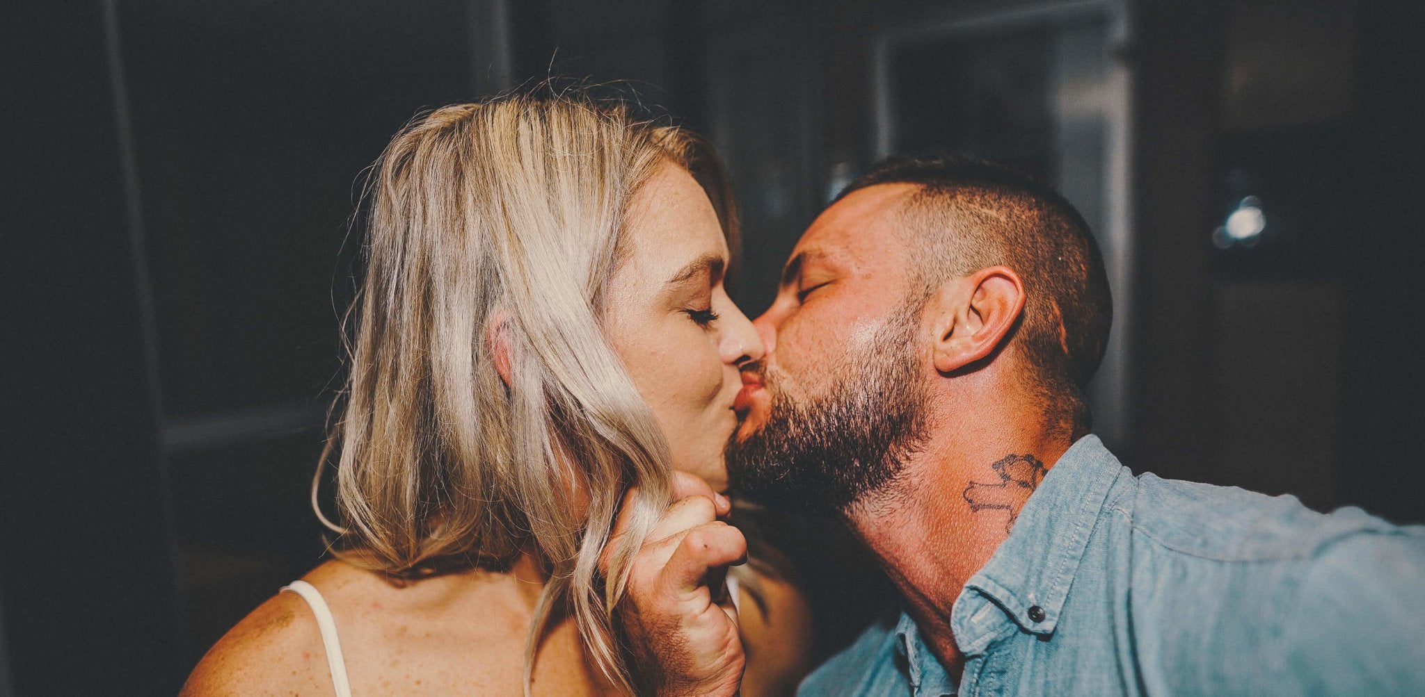 A man and woman kissing intimately, both appearing to have a natural bronze tan.