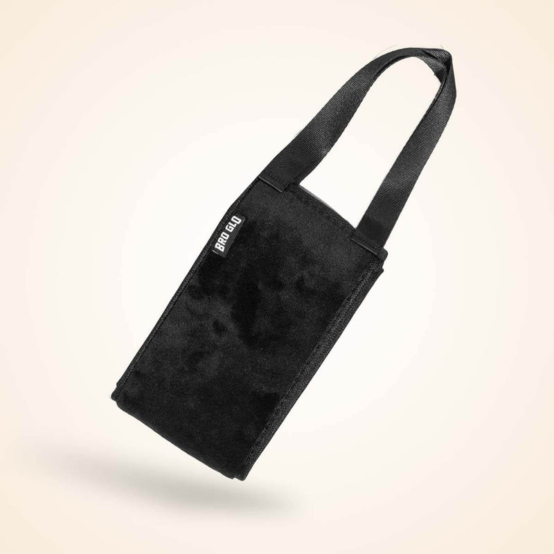 Black velvet tote bag with long handles displayed at an angle against a cream background.