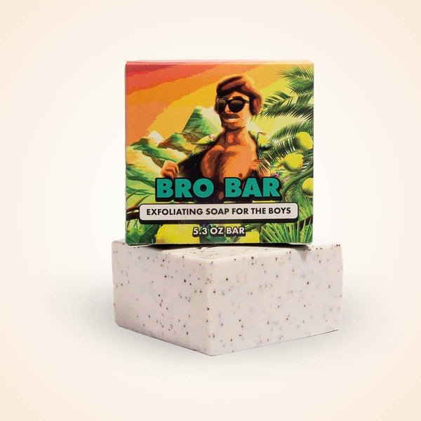 A tropical-themed soap bar with speckled white texture sits beneath its colorful packaging featuring a man in sunglasses.
