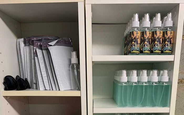 Two open cabinet shelves displaying spray bottles with white caps and applicator mitts organized neatly.