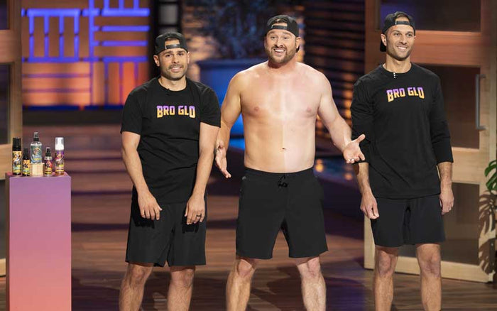 Three men on a lit stage, two wearing black 